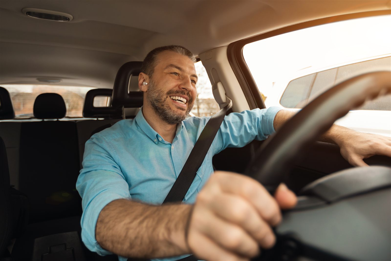 A man smiling during a hands-free call while driving